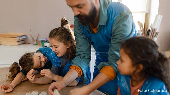 Eine Gruppe kleiner Kinder arbeitet mit ihrem Lehrer im Kunstunterricht mit Ton.