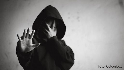 Foto zum Thema Sucht-Kriterien: Zu sehen ist eine verzweifelte Person mit einem Hoodie, die die Hand abweisend nach vorne streckt.