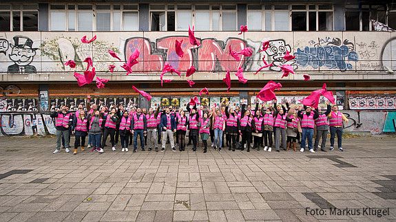 Junge Beschäftigte des öffentlichen Dienstes vor einem leerstehenden, heruntergekommenen Gebäude